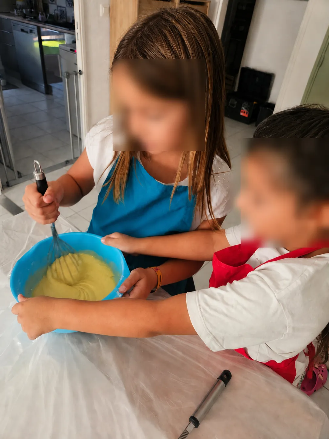 Deux enfants fouettent ensemble une pâte à gâteau dans un saladier bleu