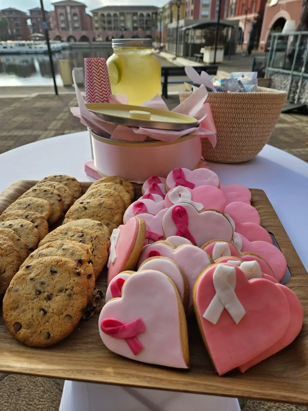 Planche de cookies aux pépites de chocolat et de biscuits sablés en forme de cœur glacés rose et blanc pour un événement d’entreprise