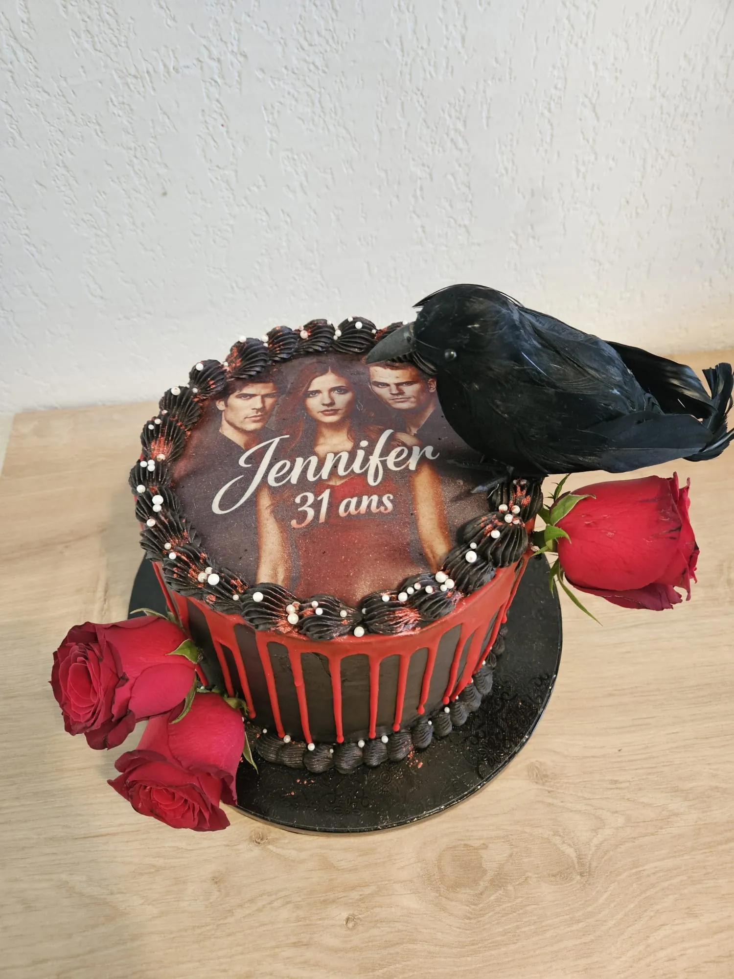 Layer cake noir et rouge avec roses fraîches et plume noire