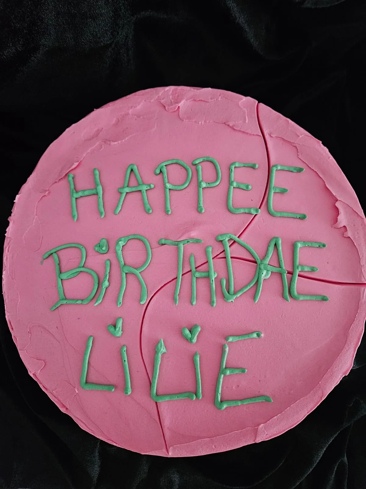Gâteau rond rose avec inscription "Happee Birtdae Lilie" en glaçage vert